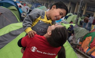 Save the children Helferin spielt mit Flüchtlingskind 