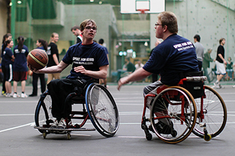 Two wheelchair users play wheelchair basketball